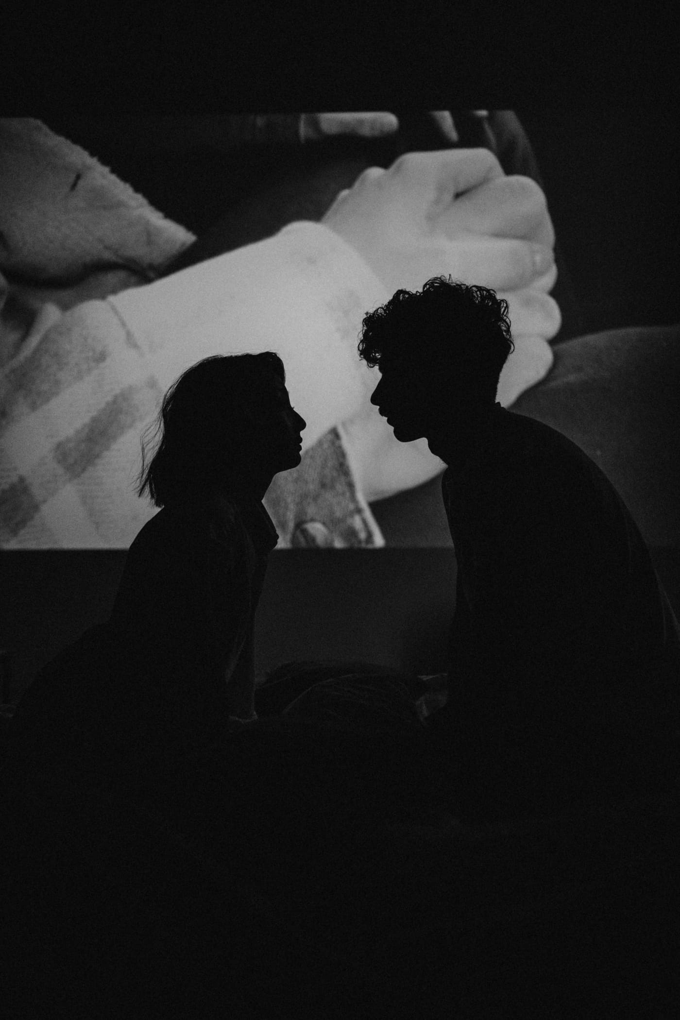 Silhouette of a couple face to face, about to kiss, in a dark moody room