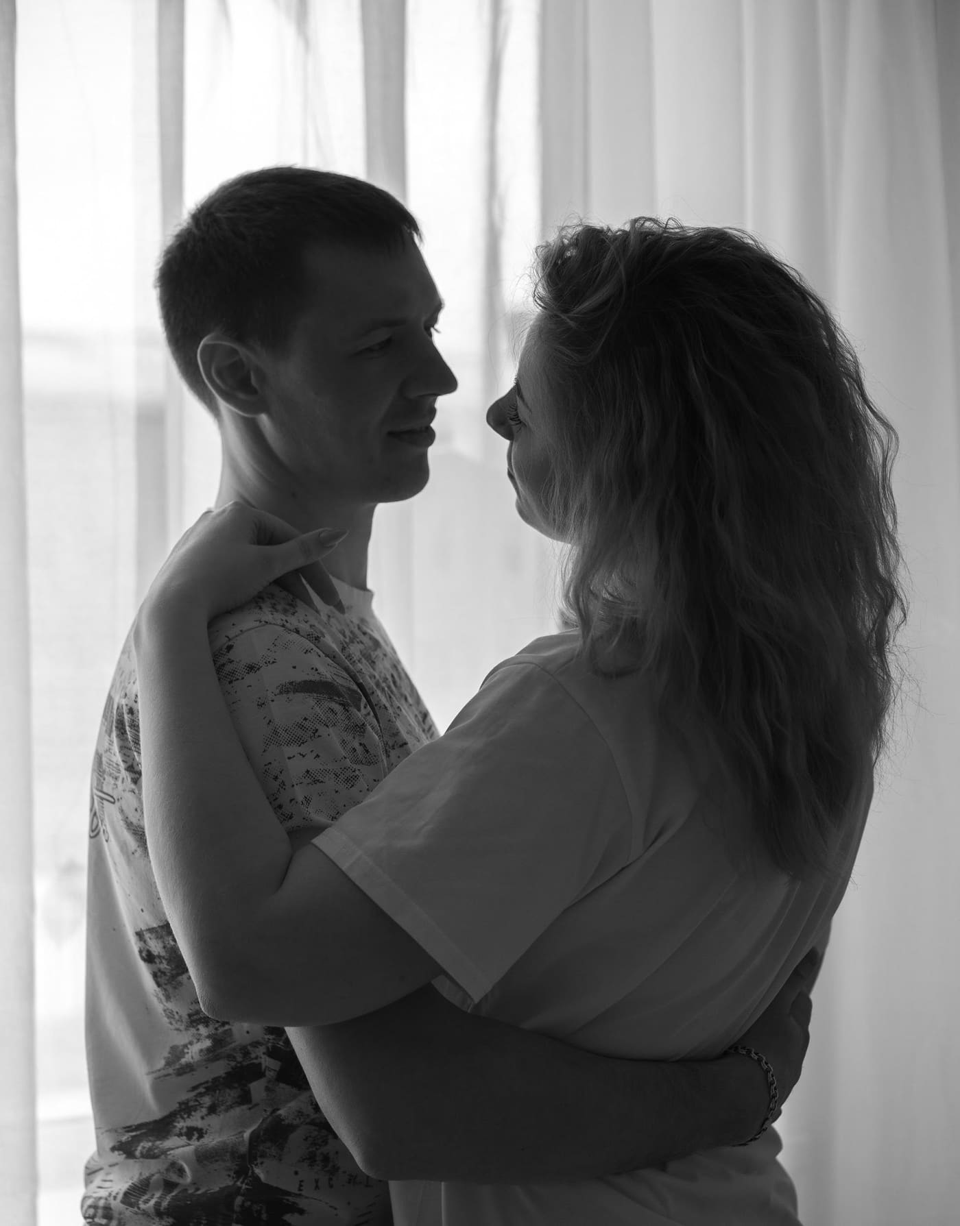 A couple embracing tenderly by a window